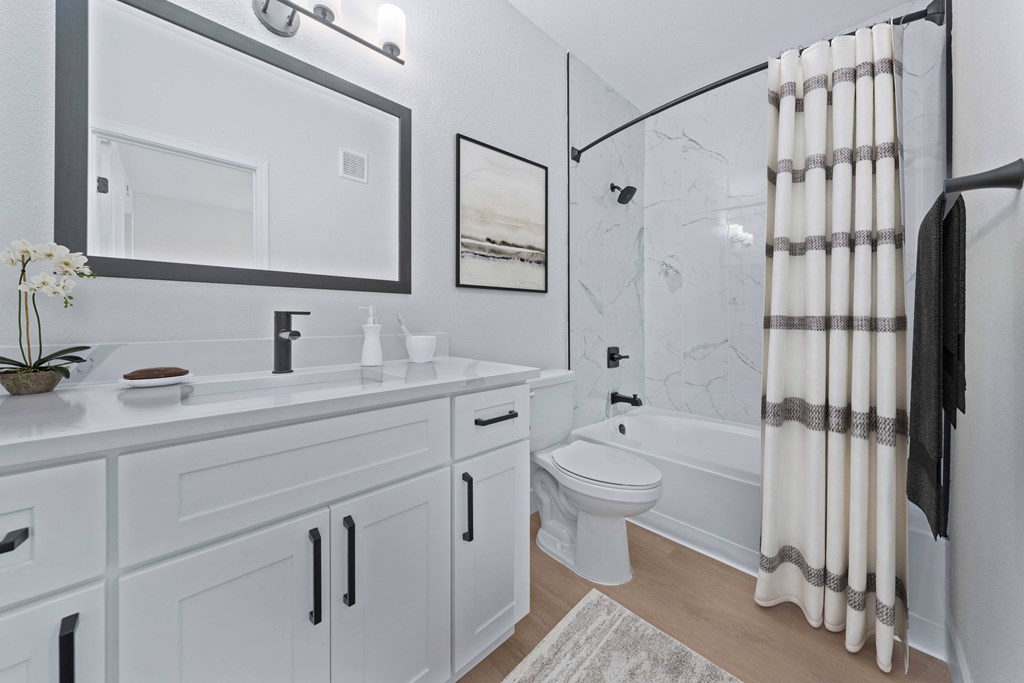 a bathroom with white cabinetry and a shower and a toilet